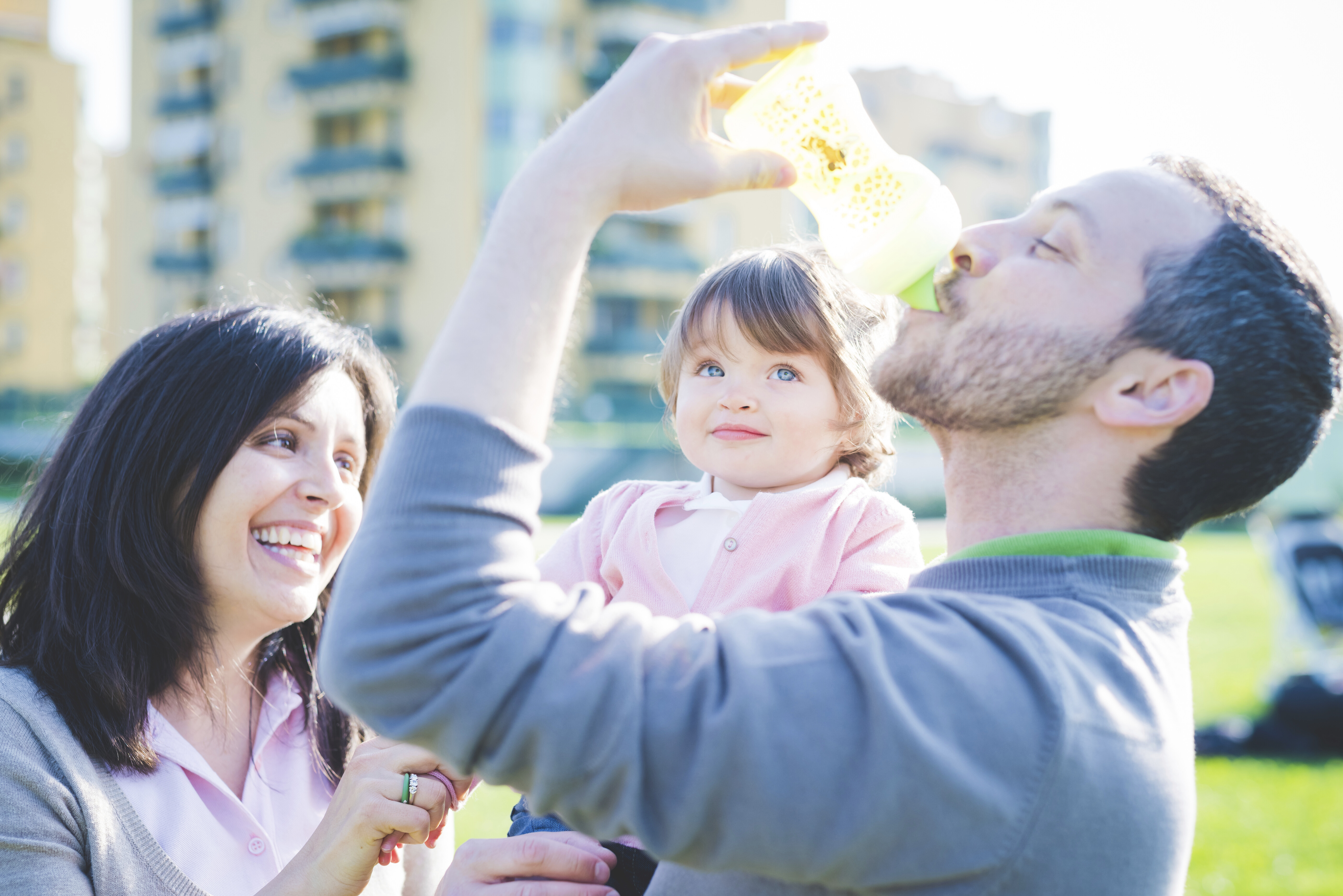 Family giving their toddler a drink of clean water outdoors