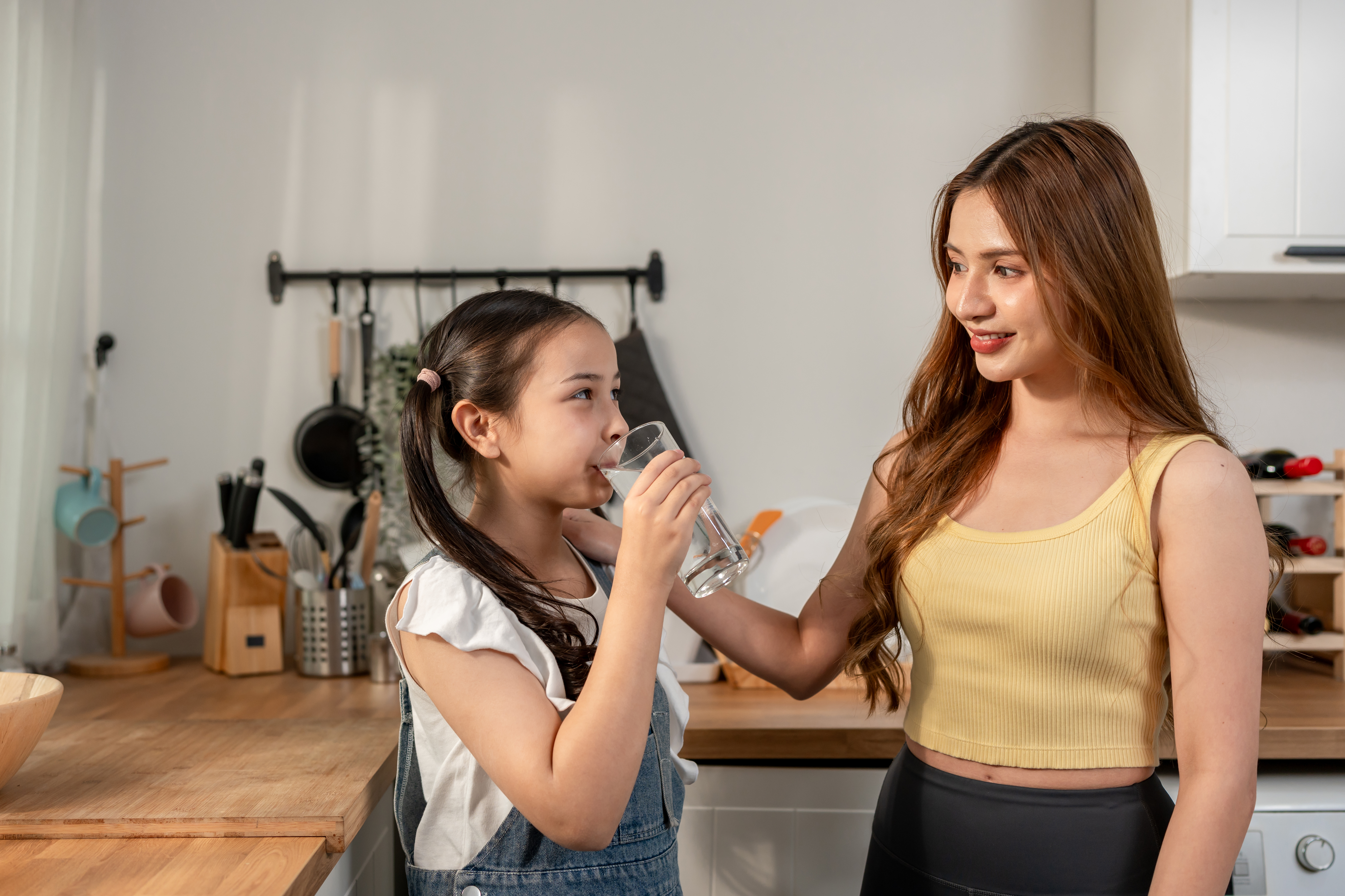 Mother and daughter drinking clean, filtered water at home