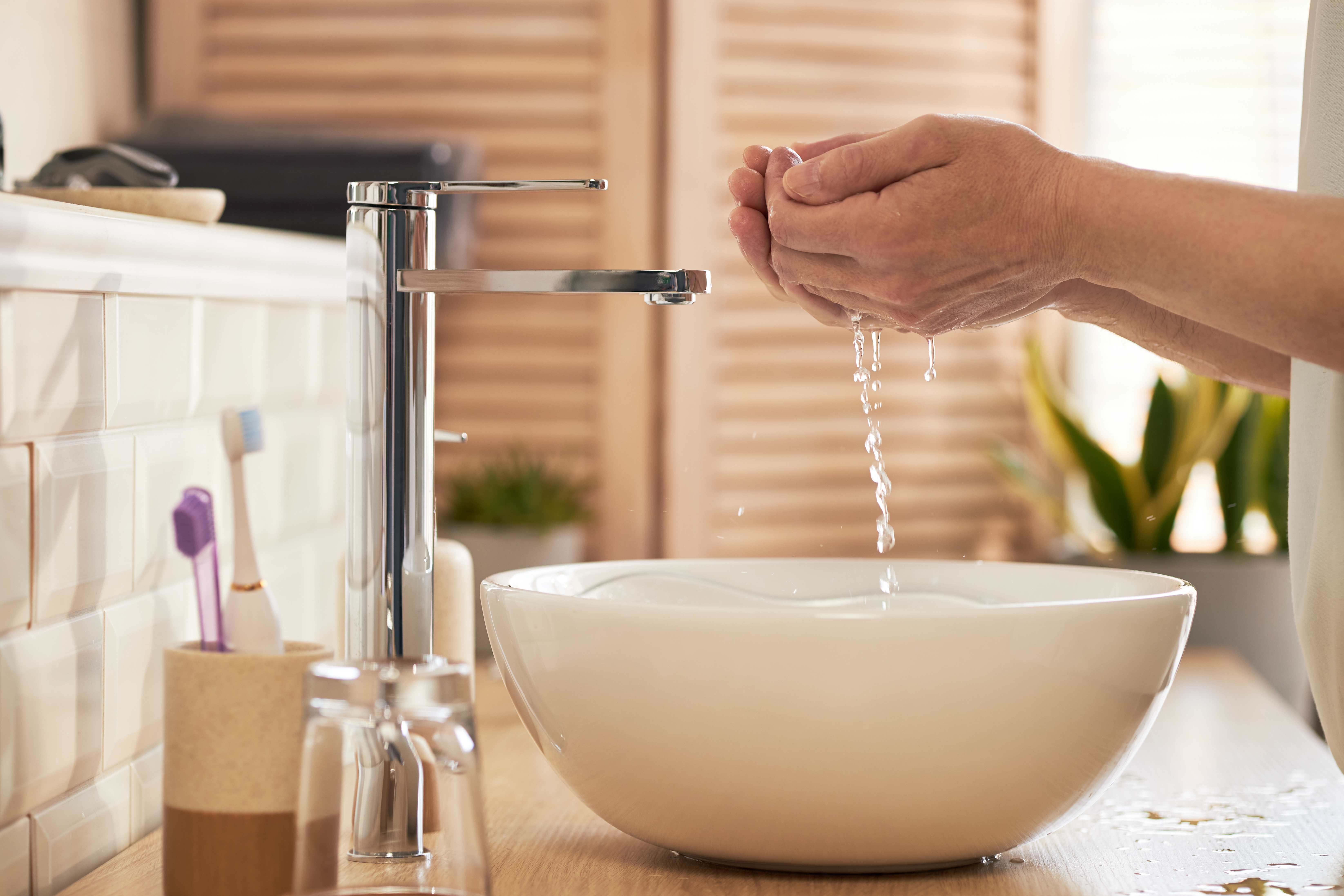 Hands washing in a bathroom sink with hard water